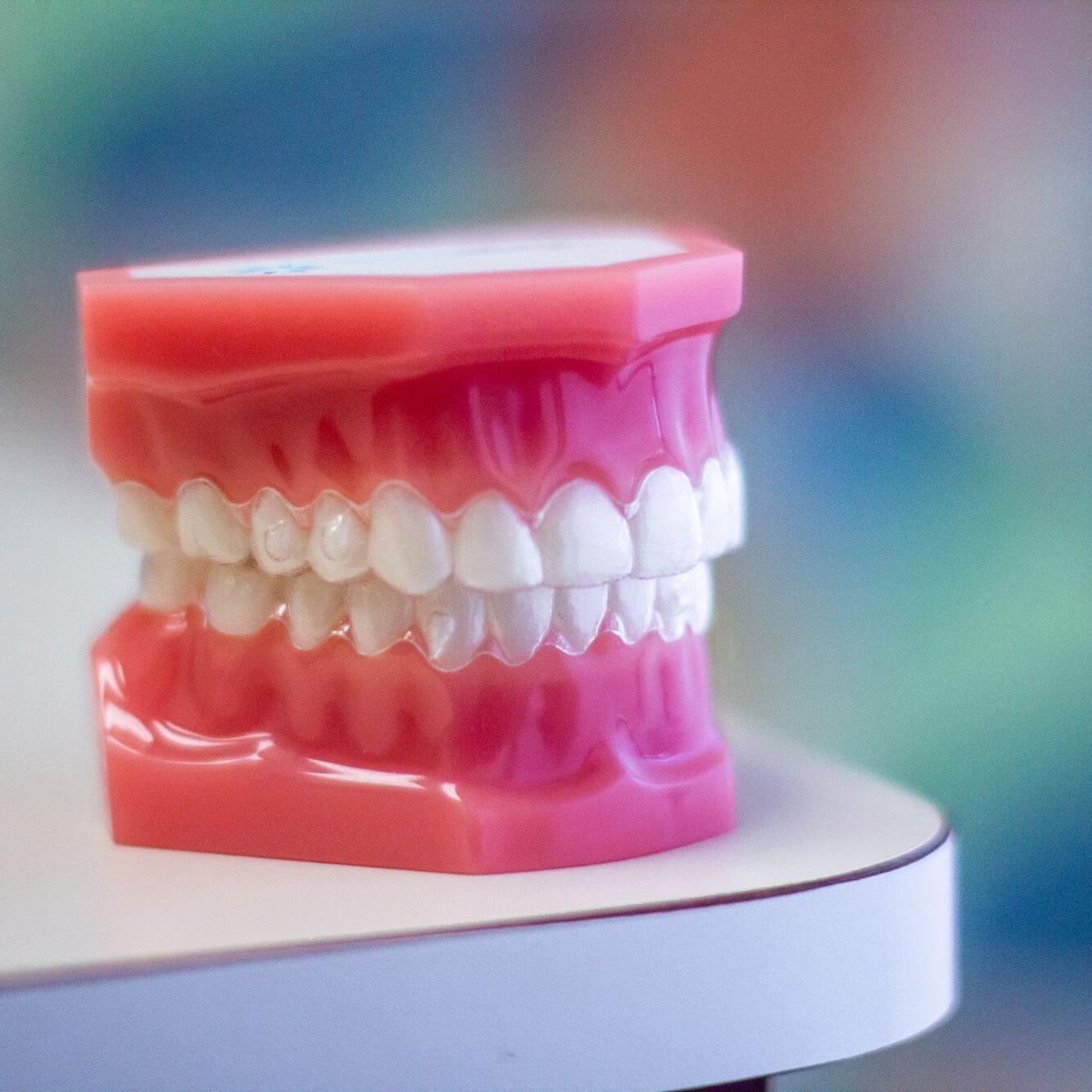 Model of teeth in pink dental mold, illustrating clear aligners, relevant to McHugh Orthodontics in Moorestown, NJ.